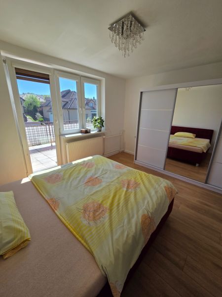 PREDAJ: rodinný dom v top lokalite Prievidze - Spálňa v rodinnom dome s posteľou, skriňou, oknom na balkón a podlahou s dreveným dekorom.
