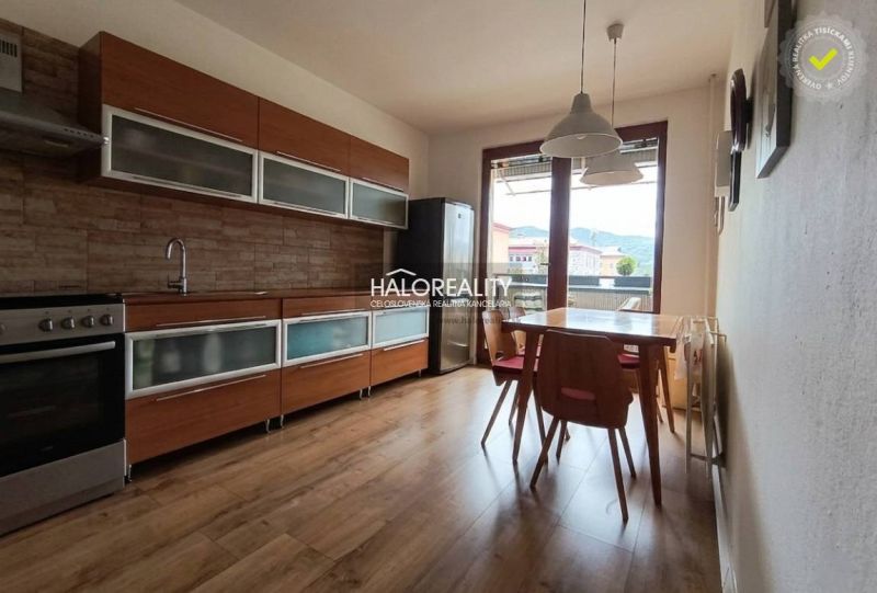 Predaj, trojizbový byt Revúca, Panoramatický výhľad ... - Kuchyňa v 3-izbovom byte s podlahou s dreveným dekorom a jedálenským stolom.