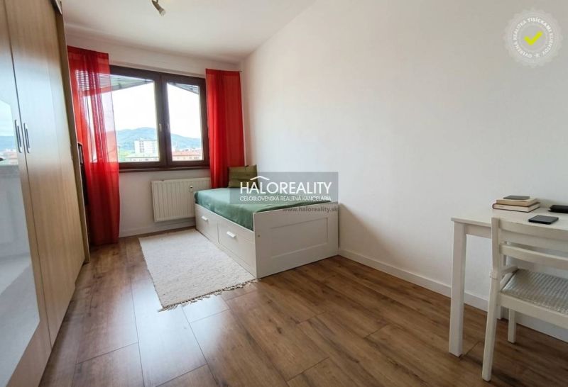 Predaj, trojizbový byt Revúca, Panoramatický výhľad ... - Svetlá izba s posteľou, stolom a podlahou s dreveným dekorom v 3-izbovom byte.
