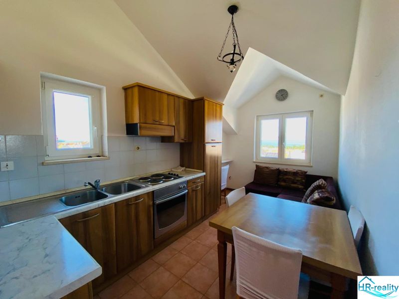 Brač(HR)–Zariadený apartmán 56m2 s výhľadom na more - Kuchyňa s dreveným dekorom, jedálenským stolom a pohovkou v rekreačnom apartmáne.