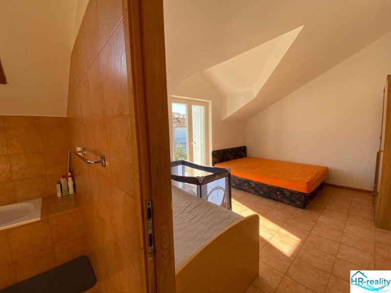 Brač(HR)–Zariadený apartmán 56m2 s výhľadom na more - Interiér rekreačného apartmánu s pohovkou, posteľou a detskou postieľkou.