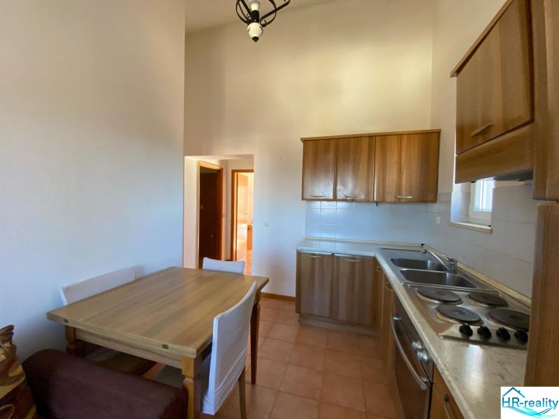 Brač(HR)–Zariadený apartmán 56m2 s výhľadom na more - Kuchyňa v rekreačnom apartmáne s drevenými skrinkami a jedálenským stolom.