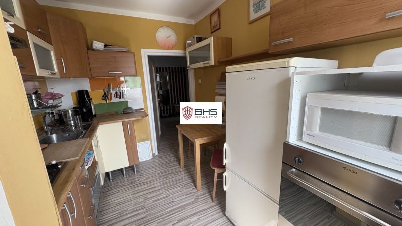 Prenájom 2i-byt s lodžiou s krásnym výhľadom na Račianskej ulici - Kuchyňa v 2-izbovom byte so žltými stenami a podlahou s dreveným dekorom.