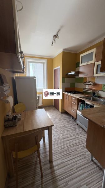 Prenájom 2i-byt s lodžiou s krásnym výhľadom na Račianskej ulici - Kuchyňa so žltými stenami, drevený nábytok a podlaha s dreveným dekorom v 2-izbovom byte.
