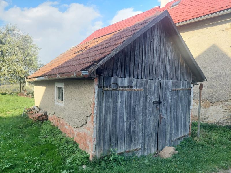 EXKLUZÍVNE NA PREDAJ – pekný pozemok na stavbu domu alebo chaty BUDINÁ - Stará drevená garáž na pozemku pre bývanie v Budinej, obklopená zeleňou a stromami.