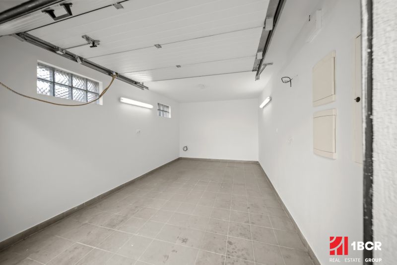 5 IZB.ROD.DOM S UNIKÁTNYM POZEMKOM - JURSKÁ, NOVÉ MESTO - Biela garáž v rodinnom dome s dlažbou a oknami z luxferov.