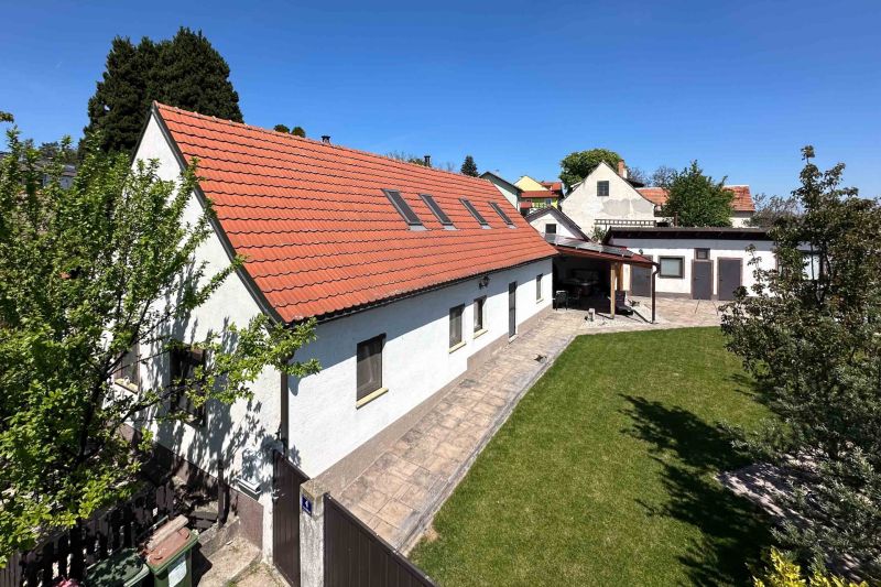 3-izbový dom s nádherným výhľadom a historickou vínnou pivnicou, Berg - Rodinný dom v meste Berg s červenou strechou a zeleným trávnikom.