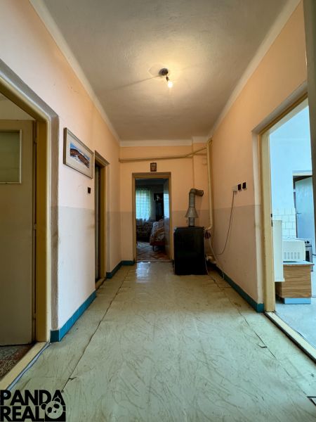 Rodinný dom v pôvodnom stave s veľkorysým pozemkom  - Chodba v rodinnom dome s jednoduchým osvetlením a starším interiérovým dizajnom.