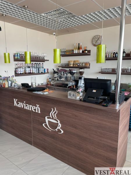 ODSTÚPENIE ZABEHNUTEJ KAVIARNE V CENTRE TRNAVY – TROJIČNÉ NÁMESTIE - Interiér kaviarne s dreveným dekorom, pultom, poličkami a kávovarom, optimalizovaný na gastro priestory.