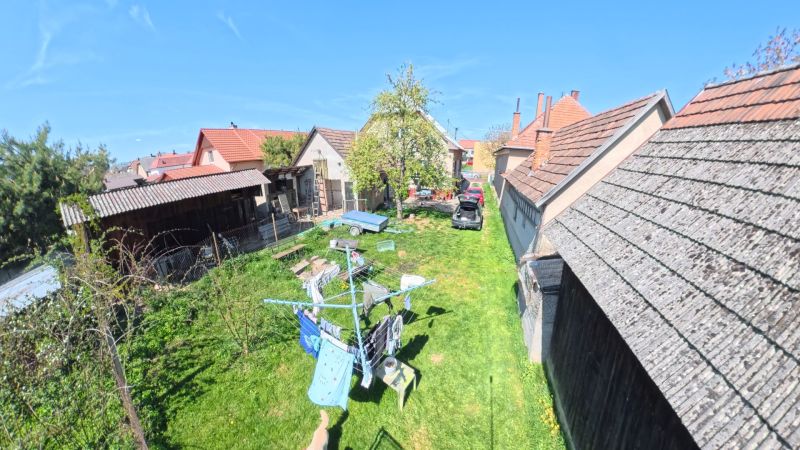 Dobré Reality ponúkajú rodinný dom s veľkou záhradou v obci Svinná  - Záhrada rodinného domu v obci Svinná s autom, prístreškom a sušiakom na prádlo.