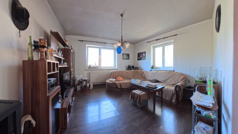 Dobré Reality ponúkajú rodinný dom s veľkou záhradou v obci Svinná  - Obývačka v rodinnom dome s tmavou podlahou a sedacou súpravou.