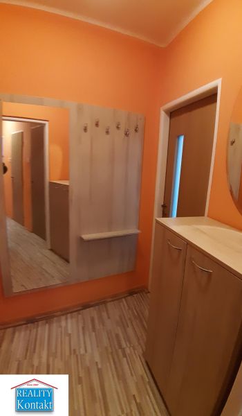 Na prenájom 2-izbový byt - Nové Zámky - Oranžová predsieň so zrkadlom, vešiakmi a podlahou s dreveným dekorom v 2-izbovom byte.