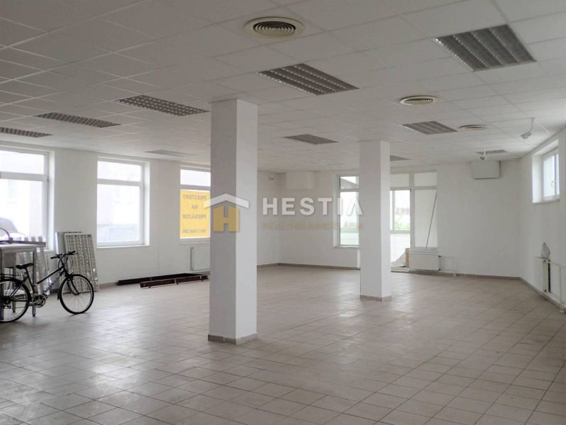 Veľký obchodný priestor na prenájom, centrum - Priestranné obchodné priestory s bicyklom a oknami, biele steny, dlažba, stĺpy.