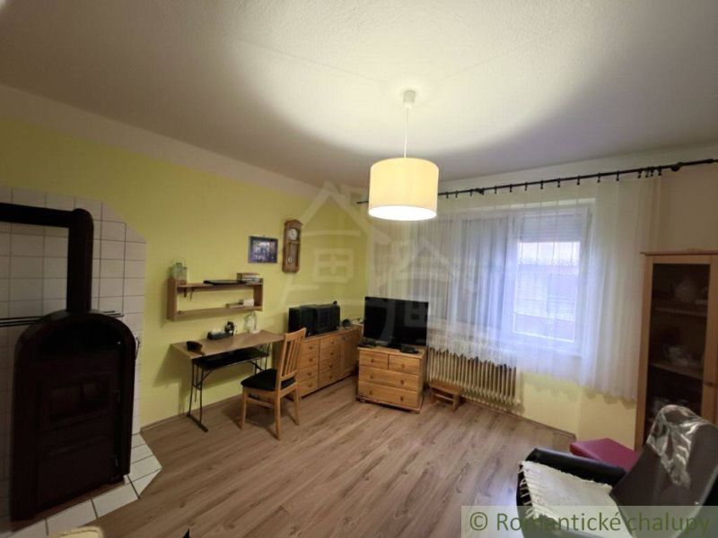 Vymením dom s veľkou záhradou v obci Mýtna za 2 i byt v Lučenci - Obývacia izba s kachľami, nábytkom z dreva a podlahou s dreveným dekorom.