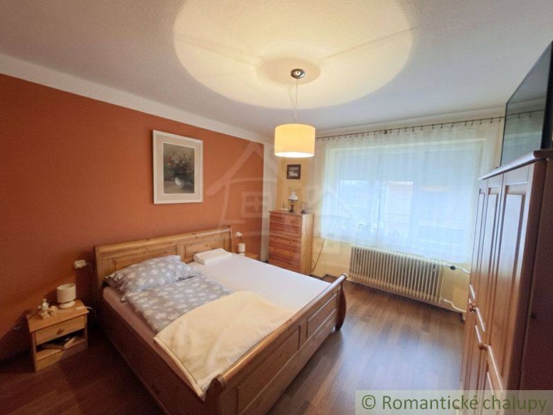 Vymením dom s veľkou záhradou v obci Mýtna za 2 i byt v Lučenci - Spálňa v rodinnom dome s dreveným dekorom, posteľou a nábytkom v teplých farbách.