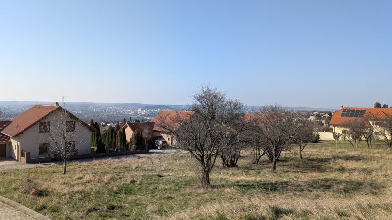 Lukratívny stavebný pozemok 936 m2 pod Zoborom, Višňová ulica - Pozemky - bývanie na Višňovej ulici v Nitre s výhľadom na mesto a domami.