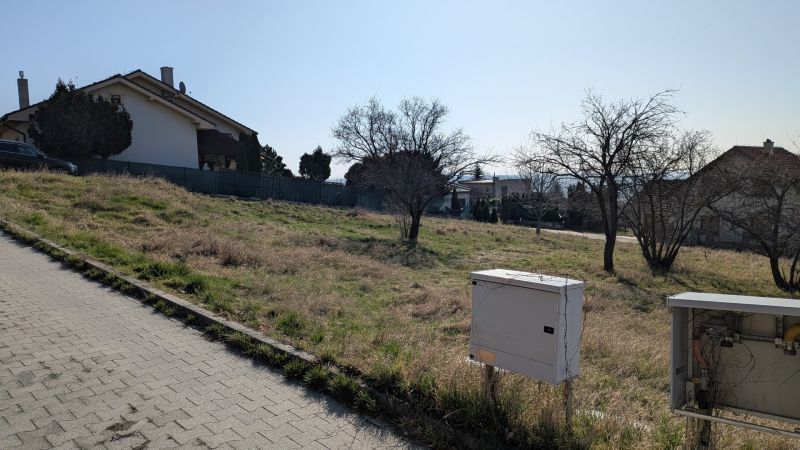 Lukratívny stavebný pozemok 936 m2 pod Zoborom, Višňová ulica - Pozemky - bývanie na Višňovej ulici v Nitre, mierne svahovitý terén s domami v pozadí.