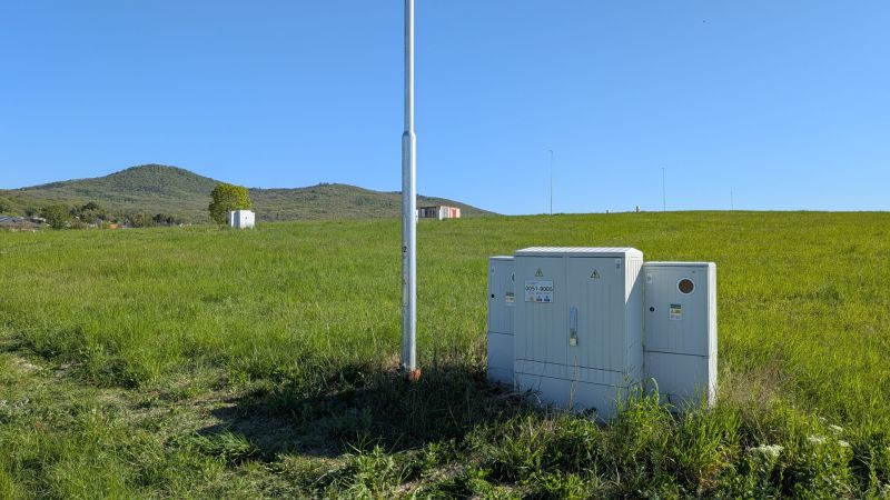 Stavebný pozemok 601 m2 v Štitároch - Zeleň na pozemku pre bývanie v Štitároch, s technickými skrinkami a horskou panorámou.