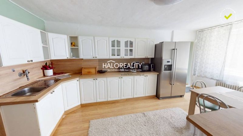 Predaj, rodinný dom Vitanová - EXKLUZÍVNE HALO REALITY - Kuchyňa v rodinnom dome s bielymi skrinkami, chladničkou a podlahou s dreveným dekorom.