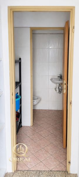 *Prenájom obchodného priestoru s výkladom, 26,3 m² – Račianske mýto* - Kúpeľňa v obchodných priestoroch s toaletou a umývadlom, jednoduchý dlažbový dizajn.