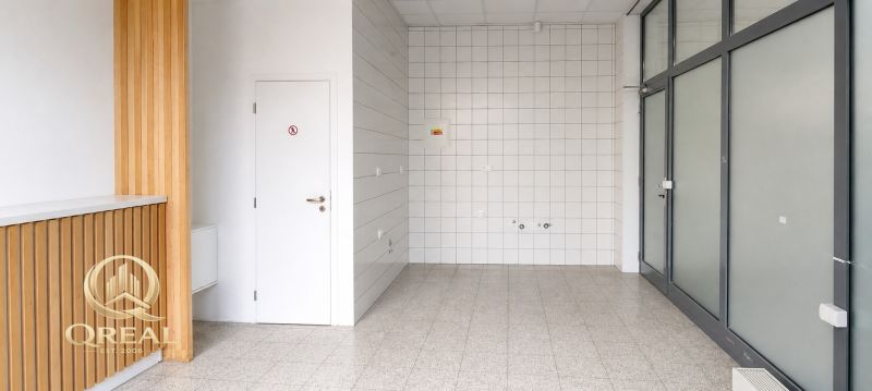 *Prenájom obchodného priestoru s výkladom, 26,3 m² – Račianske mýto* - Obchodné priestory so svetlou podlahou, bielymi dlaždicami a dreveným dekorom na stene.