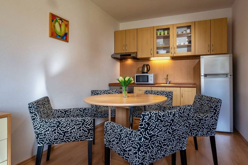 Príjemný rekreačný apartmán priamo pod zjazdovkou v Telgárte - Kuchynský kút s jedálenským stolom a kreslami v Rekreačnom apartmáne, podlaha s dreveným dekorom.