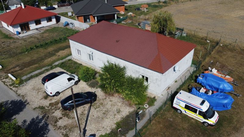 NA PREDAJ 3-IZBOVÝ RD (ČASŤ DVOJDOMU), ZEMIANSKA OLČA - Rodinný dom v Zemianskej Olči s áutami zaparkovanými na štrkovom pozemku a zahaleným vybavením.