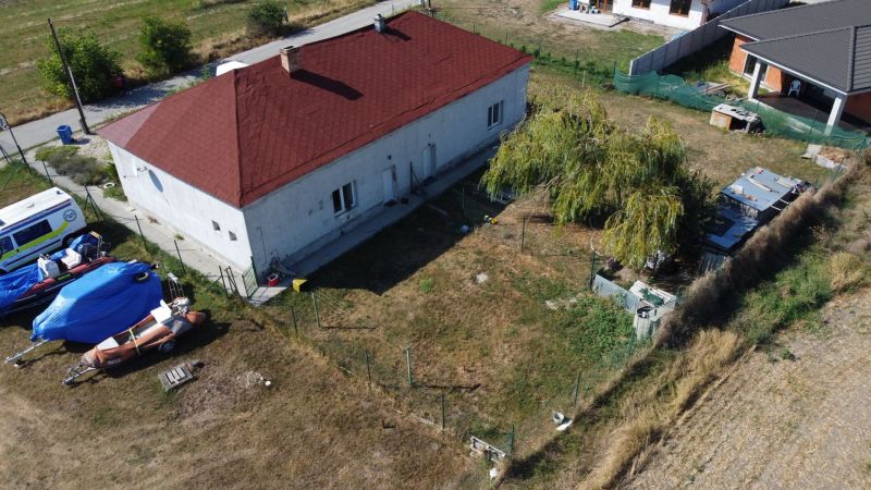 NA PREDAJ 3-IZBOVÝ RD (ČASŤ DVOJDOMU), ZEMIANSKA OLČA - Rodinný dom v Zemianskej Olči s červenou strechou, trávnikom a lodnými prívesmi na dvore.
