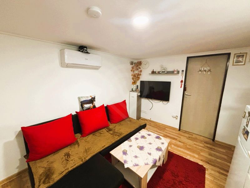 Celoročne obývateľná chata v Gabčíkove na 150 m² pozemku pri Dunaji - Obývacia izba v chate s podlahou s dreveným dekorom a červenými doplnkami.