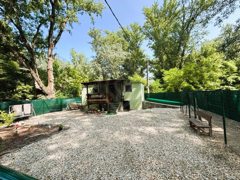 Celoročne obývateľná chata v Gabčíkove na 150 m² pozemku pri Dunaji - Chata v Gabčíkove s dvomi lavičkami na dvore obklopenom stromami.