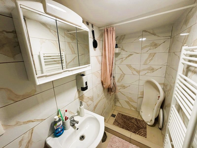 Celoročne obývateľná chata v Gabčíkove na 150 m² pozemku pri Dunaji - Kúpeľňa v chate s bielym umývadlom, zrkadlovou skrinkou a sprchovacím kútom.