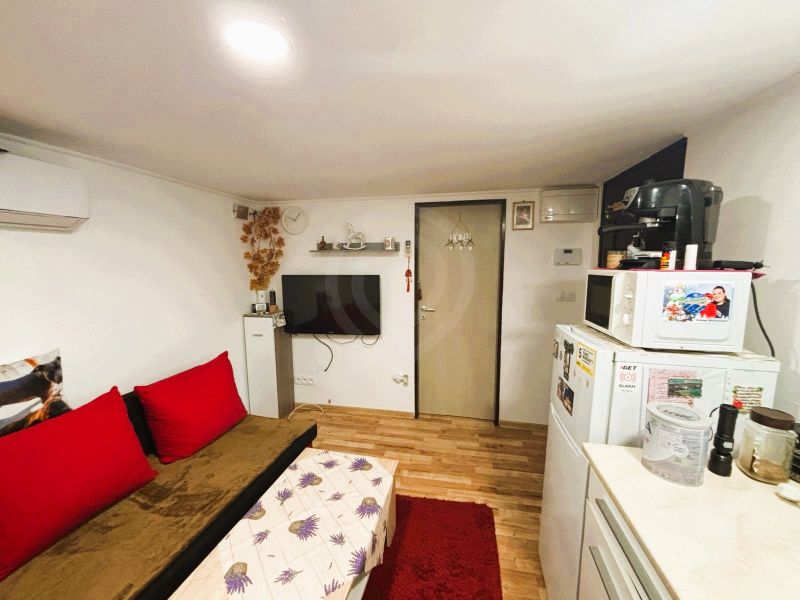 Celoročne obývateľná chata v Gabčíkove na 150 m² pozemku pri Dunaji - Obývacia miestnosť v chate s podlahou s dreveným dekorom a červenými prvkami.