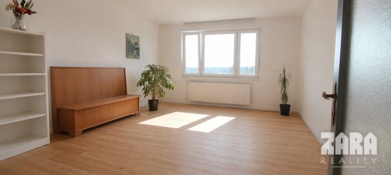 Ťahanovce - 4 izbový byt,  82 m2 + loggia. Krásny výhľad na mesto - Obývacia izba so svetlou podlahou s dreveným dekorom a rastlinami v 4-izbovom byte.