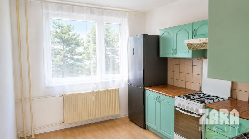 Ťahanovce - 4 izbový byt,  82 m2 + loggia. Krásny výhľad na mesto - Kuchyňa v 4-izbovom byte s plynovým sporákom, čiernou chladničkou a dreveným dekorom.