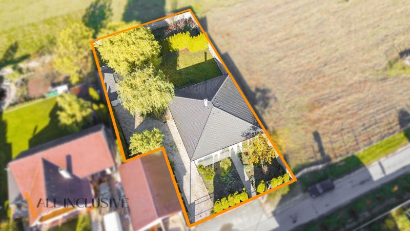 NA PREDAJ 4-IZBOVÝ RODINNÝ DOM V TOMÁŠIKOVE - Letecký pohľad na rodinný dom v Tomášikove, obklopený záhradou a stromami.