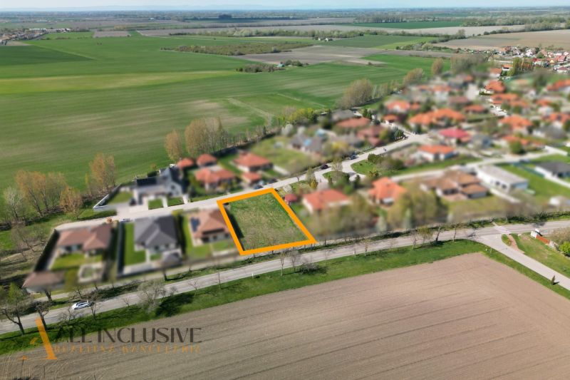 Na predaj 1046 m² stavebný pozemok, Malé Dvorníky - Pozemky - bývanie v Malých Dvorníkoch, zasadené medzi úhľadné rodinné domy a zelené polia.