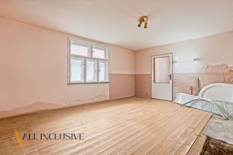 NA PREDAJ 4-IZBOVÝ RODINNÝ DOM V OBCI MOSTOVÁ - Opustená miestnosť v rodinnom dome s podlahou s dreveným dekorom a oprýskanou omietkou.
