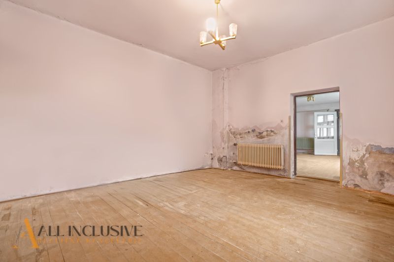 NA PREDAJ 4-IZBOVÝ RODINNÝ DOM V OBCI MOSTOVÁ - Izba v rodinnom dome s radiátorom a podlahou s dreveným dekorom, potrebujúca renováciu.