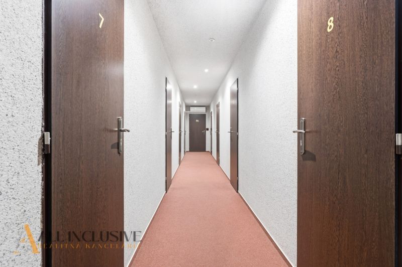 Na prenájom podnikateľské priestory, Senec - Hotelová chodba s číslovanými dverami a červeným kobercom.