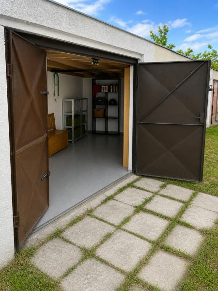 Iba u nas predaj garaže  - Otvorená garáž na Gúgskej ulici v Nových Zámkoch s regálmi a rovným trávnikom.