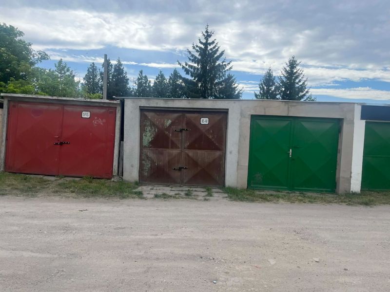 Iba u nas predaj garaže  - Garáže na ulici Gúgska v Nových Zámkoch s farebnými bránami a vegetáciou okolo.