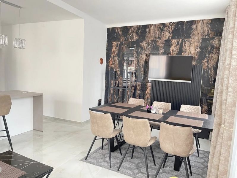 Veľkorysý 3 izbový byt 87m2 po rekonštrukcii, Wiener Neustadt - Jedáleň so stolom a šiestimi stoličkami, podlaha s dreveným dekorom, televízor na stene.