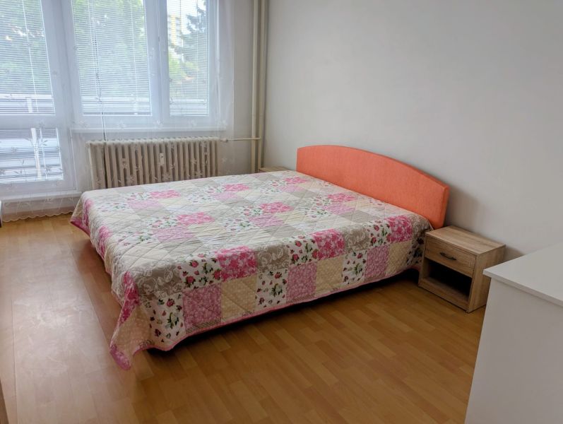2izbový byt na prenájom v Dubnici nad Váhom  - Spálňa s posteľou a patchworkovým prehozom v 2-izbovom byte, podlaha s dreveným dekorom.