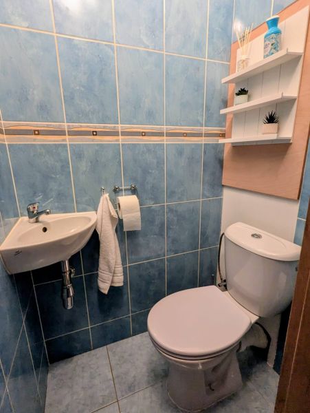 2izbový byt na prenájom v Dubnici nad Váhom  - Kúpeľňa s modrými kachličkami a toaletou v 2-izbovom byte, police na stene.