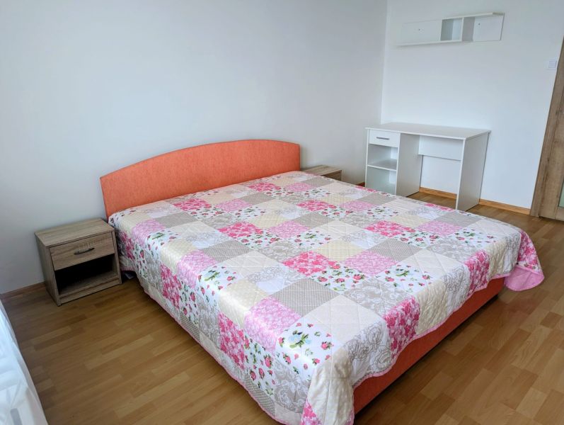 2izbový byt na prenájom v Dubnici nad Váhom  - Spálňa v 2-izbovom byte s posteľou, písacím stolom a podlahou s dreveným dekorom.