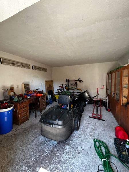 Vidiecky dom na predaj Mikulášov - Garáž v rodinnom dome s rôznym náradím a pojazdnou kosačkou.