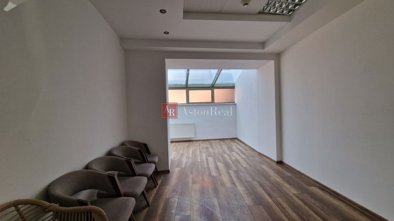PRENÁJOM Priestory Poprad - Námestie Sv.Egídia - prízemie - 35 m2 - Interiér obchodných priestorov s podlahou s dreveným dekorom a stoličkami pri stene.