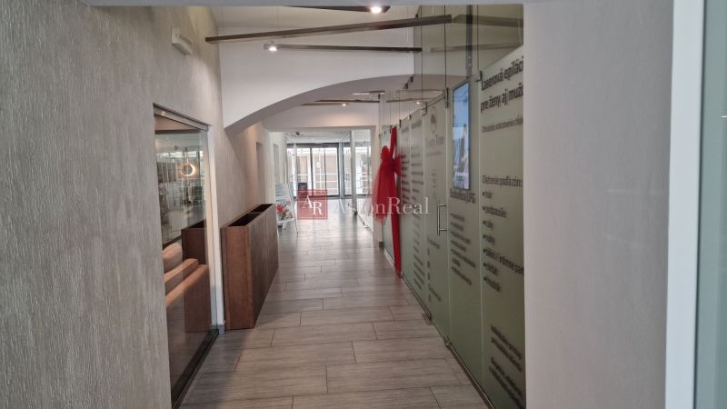 PRENÁJOM Priestory Poprad - Námestie Sv.Egídia - prízemie - 35 m2 - Interiér obchodných priestorov s dlhým chodbovým priestorom, presklenými stenami a svetlou podlahou.