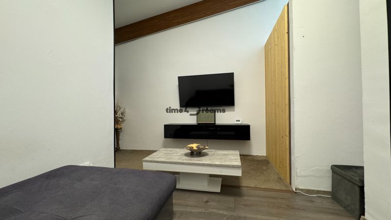 ODSTÚPENIE gastro prevádzky PIZZA Top v Nitre - Minimalistický interiér s TV, konferenčným stolíkom a drevenou stenou, ktorý prináša komfort.