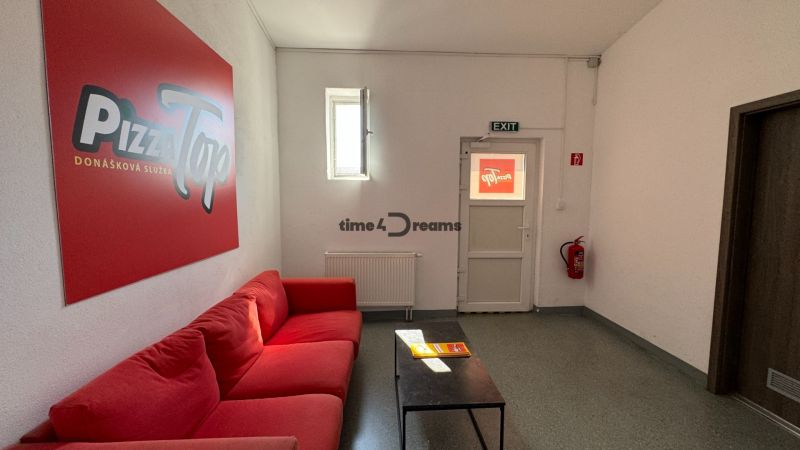ODSTÚPENIE gastro prevádzky PIZZA Top v Nitre - Červená pohovka a stolík, služby donášky, gastro priestory, núdzový východ a hasičský prístroj.